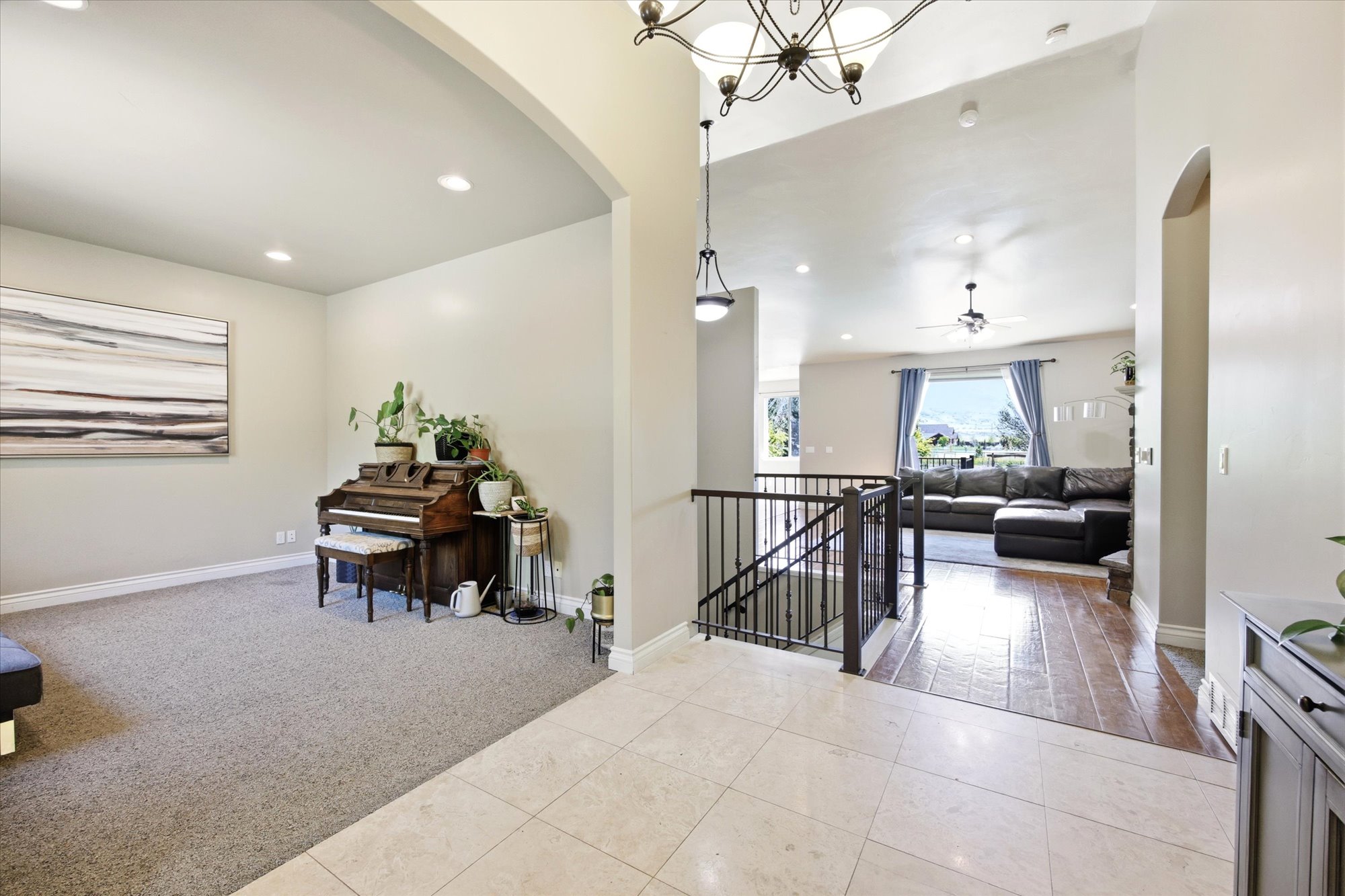 Entryway featuring tile flooring, a wrought iron stair railing, and an arched doorway leading to a carpeted room