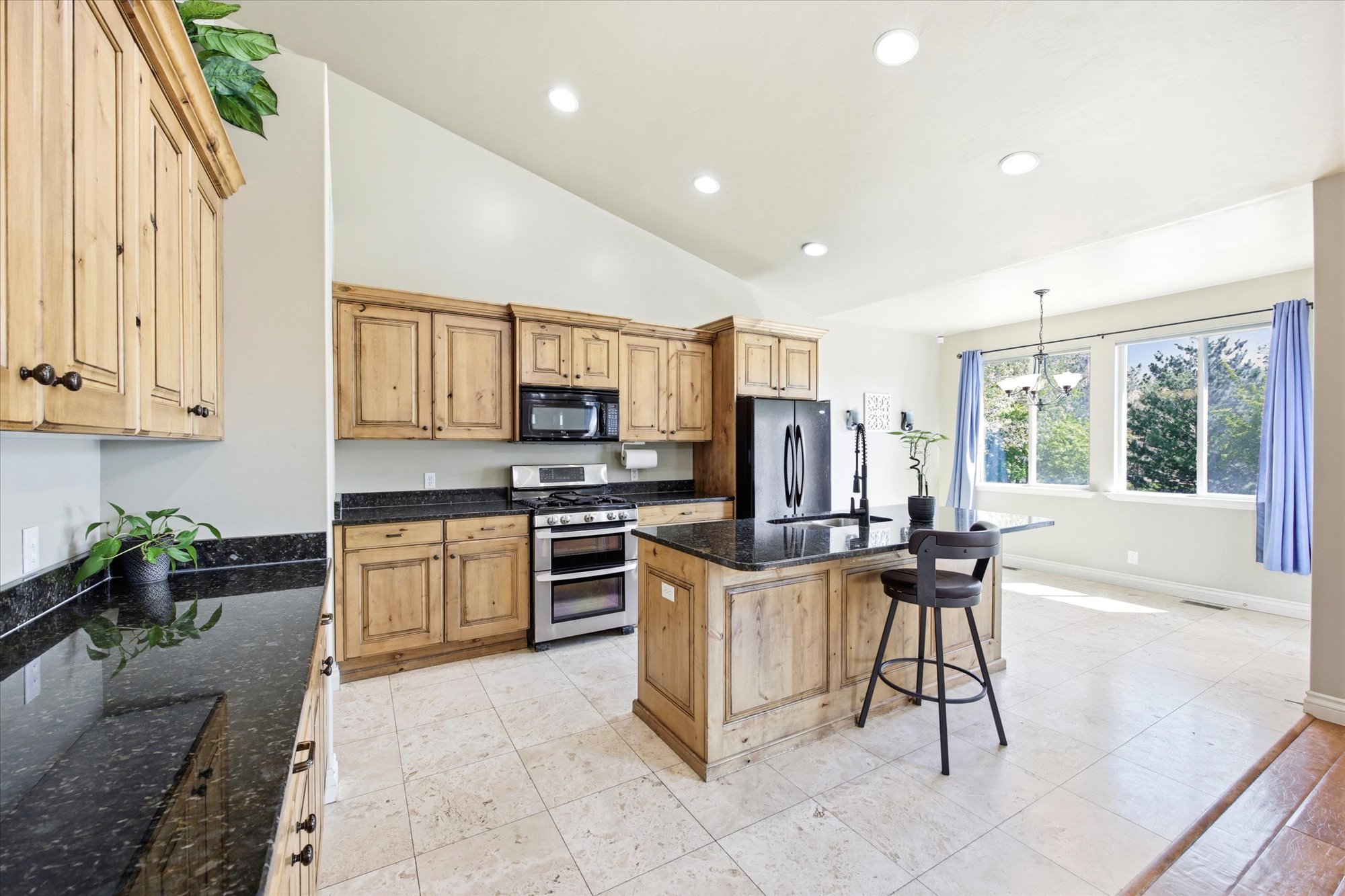 Kitchen featuring natural wood cabinetry, dark countertops, a stainless steel range with double ovens, a center island with seating, and recessed lighting
