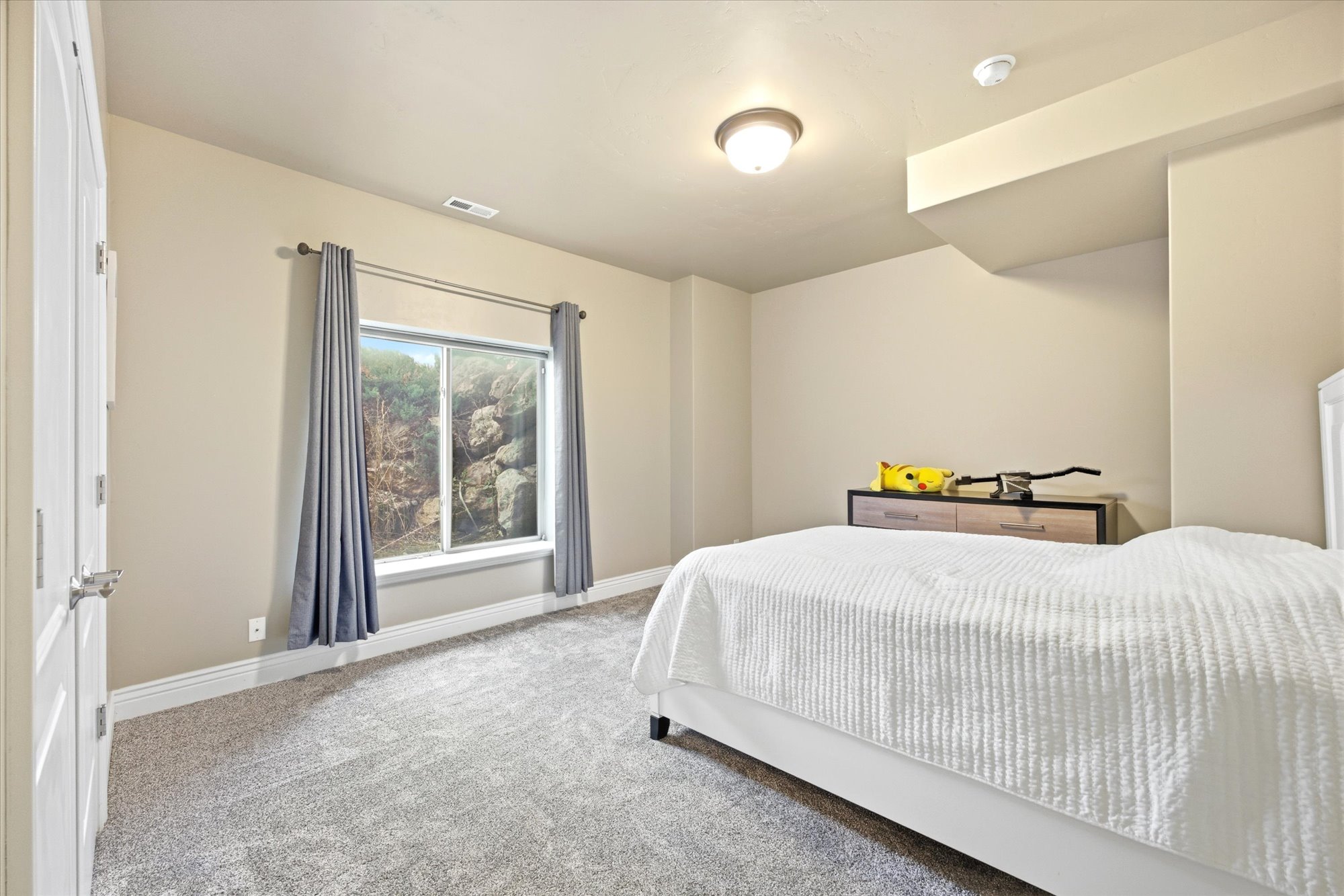 Carpeted interior with a single window, white trim, and neutral wall tones