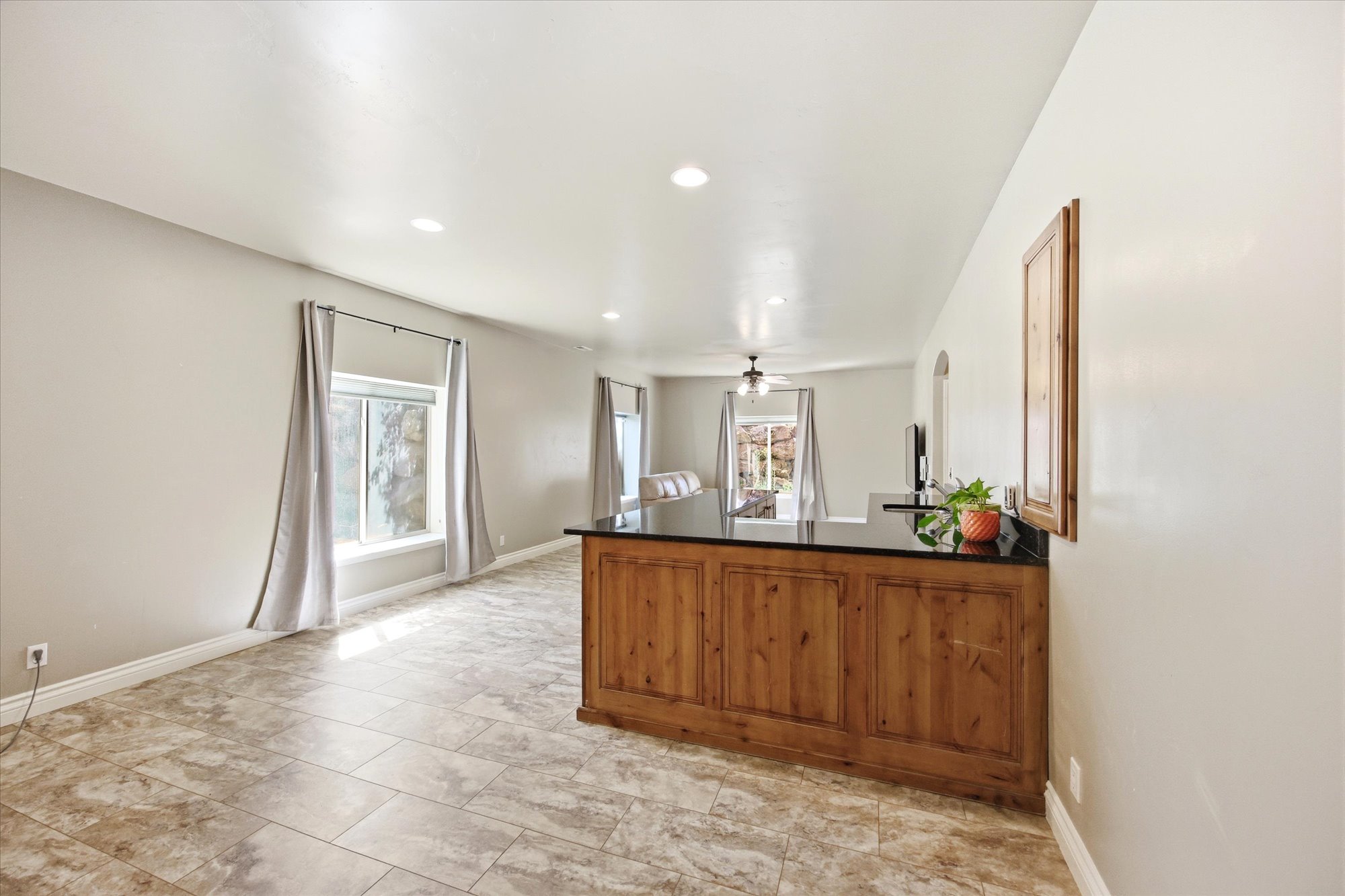 Open-concept living area featuring wood-finish cabinetry with a dark countertop, recessed lighting, and tile flooring