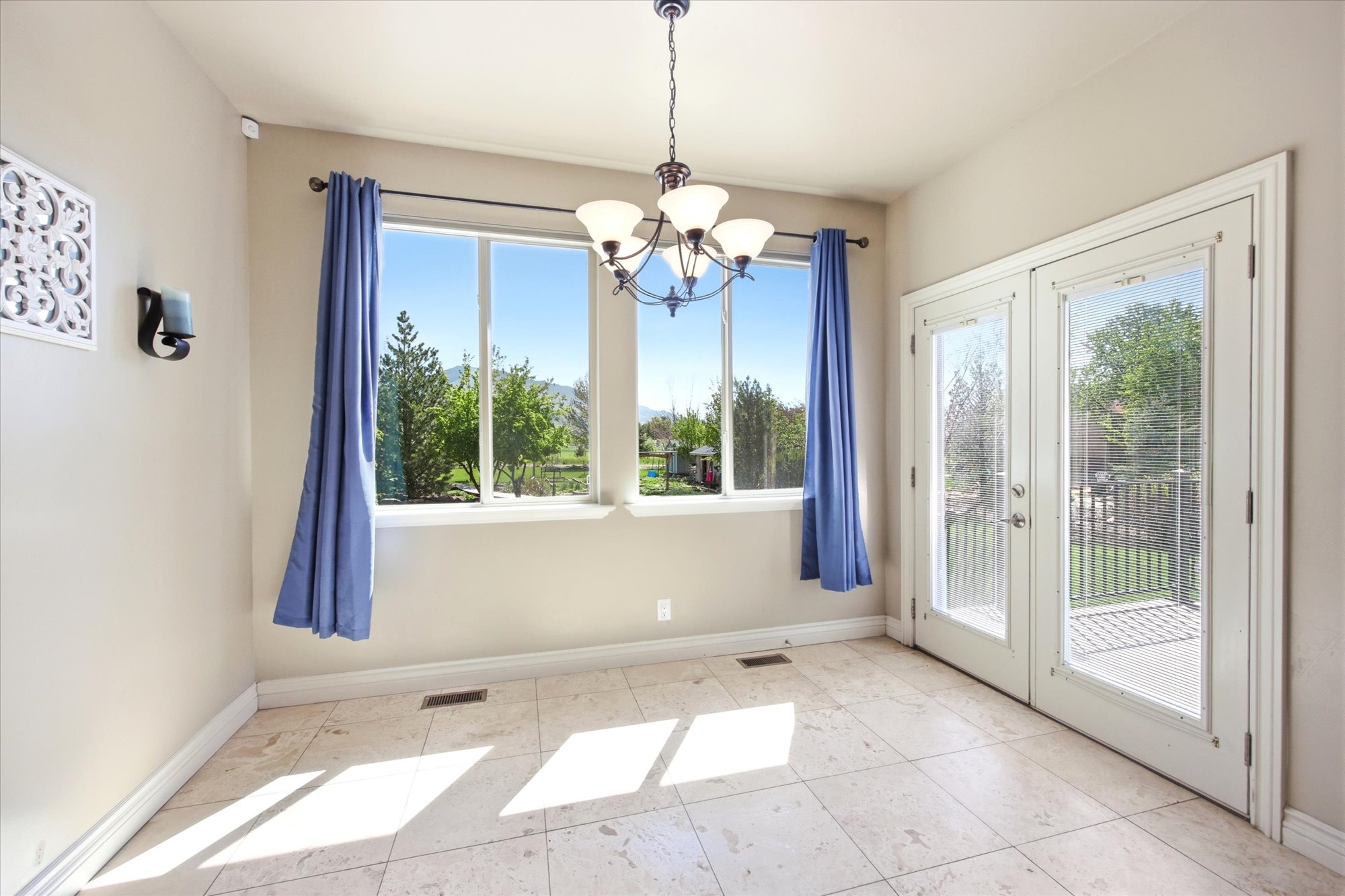 Spacious room featuring tile flooring, a multi-pane window, and French doors providing direct outdoor access to a patio