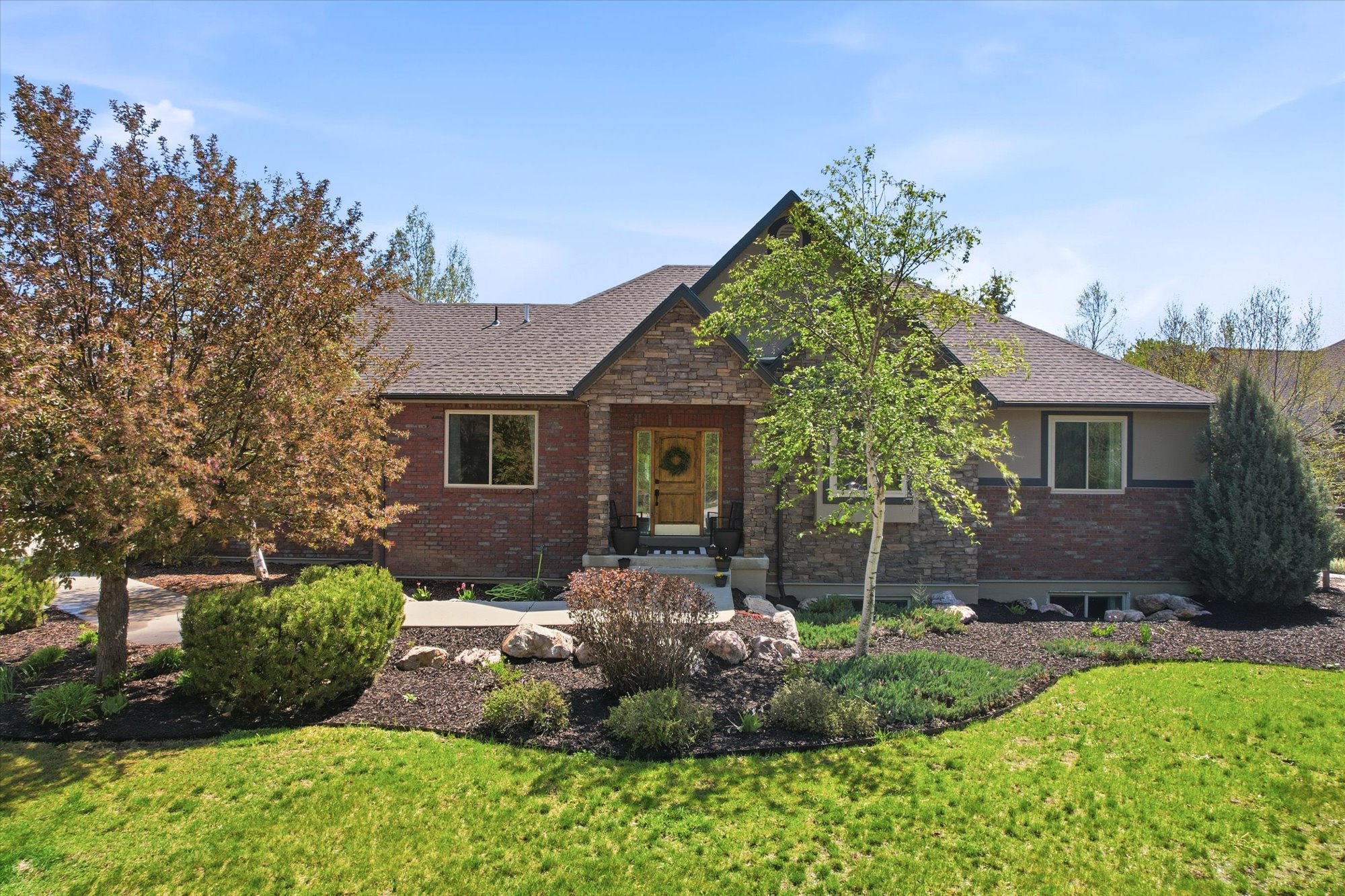 Ranch-style residence featuring a brick and stone facade, gabled roofline, and a welcoming covered entry