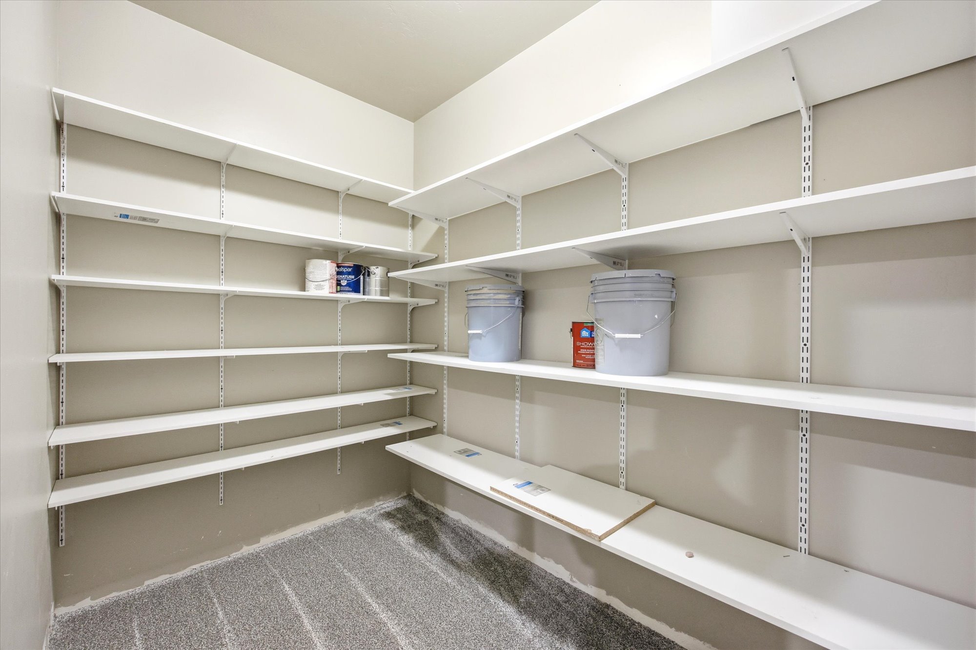 Expansive pantry featuring multi-level shelving, white-painted walls, and a durable floor finish