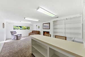 Spacious room featuring a white brick fireplace with a visible flame, built-in shelving, a built-in counter with open shelving, and a large window