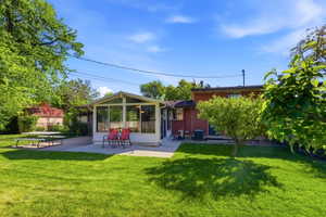 Expansive green lawn with mature trees and a sunny sunroom addition
