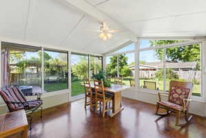 Sunroom with an angled ceiling and exposed beams, featuring an overhead ceiling fan with light fixture