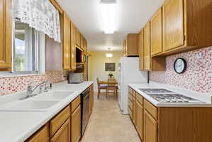 Galley kitchen featuring wood-finish cabinetry, white countertops, a mosaic tile backsplash, and tile flooring