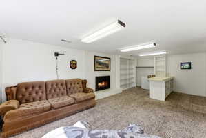 Spacious room featuring a white brick fireplace, built-in shelving, a wet bar with a countertop, and carpet flooring