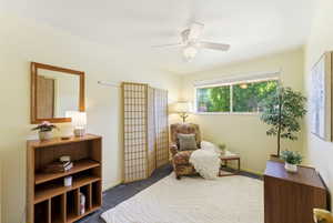 Room featuring a ceiling fan, broad window, and carpet flooring