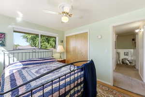 Windowed room featuring a ceiling fan with integrated lighting, wood-finish flooring, and a double-door closet with wood-finish bi-fold doors