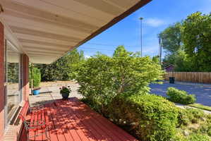 Covered front porch featuring a red-stained wood deck and brick exterior