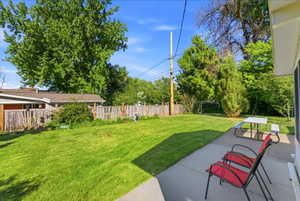 Expansive backyard featuring a lush lawn, mature perimeter trees, and a full privacy fence