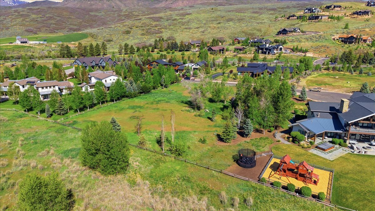 Expansive property featuring a large green space, established trees, and a distant mountain backdrop