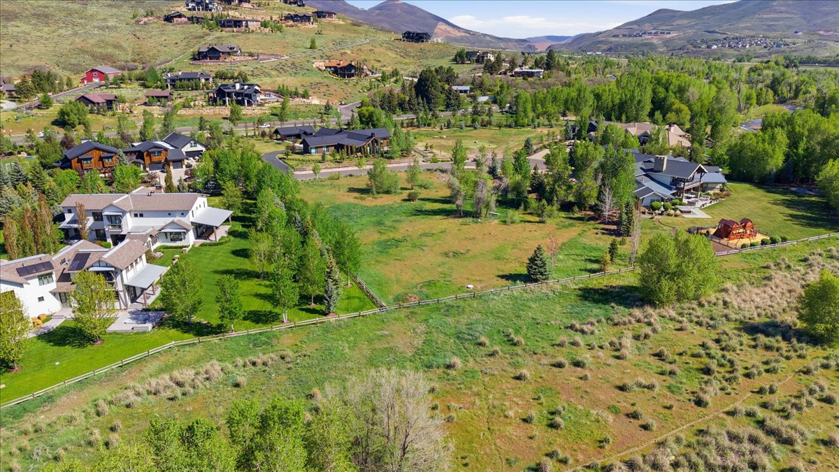 Expansive aerial landscape highlighting a verdant hillside setting with multiple residential properties