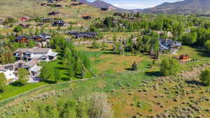 Expansive aerial landscape highlighting a verdant hillside setting with multiple residential properties