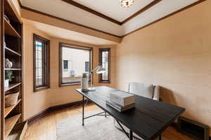 Bay window with multiple windows, wood-finish flooring, built-in shelving, wood trim, and a decorative ceiling light fixture
