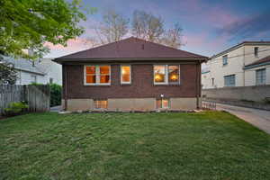 Expansive grassy area bordering a brick exterior with multiple windows and a brown shingle roof