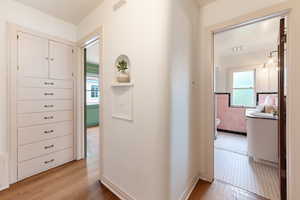 Hallway featuring built-in cabinetry with multiple drawers, wood-finish flooring, and a decorative wall niche