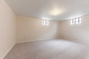 Spacious room featuring light neutral wall paint and light gray carpet flooring