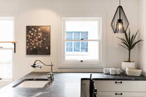 Kitchen featuring a deep undermount sink with a gooseneck faucet, dark countertop with light veining, and white cabinetry with matte black hardware