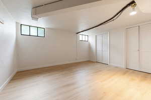 Spacious room featuring wood-finish flooring, white painted walls, and white baseboards