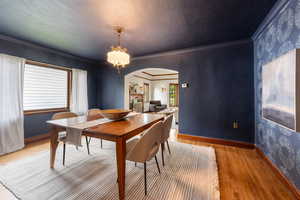 Dining area featuring wood-finish flooring, a decorative chandelier, and a large window