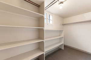 Closet storage room featuring multiple built-in shelving units, a hanging rod, a small window, and a ceiling-mounted light fixture