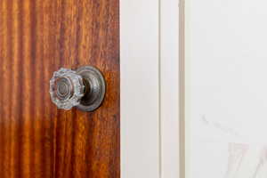 Solid wood door featuring a natural grain finish and a decorative glass door knob with an antique-finish escutcheon