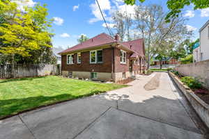 Brick exterior with a red shingle roof, concrete driveway, gravel median, landscaped bed, and a fenced lawn