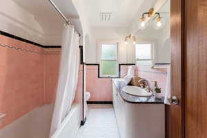 Bathroom with pink tiled walls, black trim, and a white bathtub