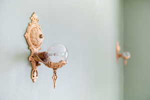 Ornate wall sconce with detailed carvings and a clear bulb, set against a light green wall