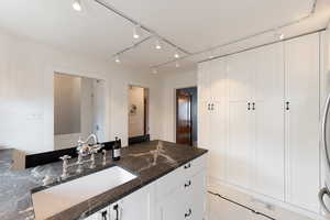 Kitchen island featuring a farmhouse sink and stone countertop