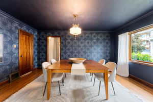 Hardwood flooring complements a decorative wall covering and a wood-trimmed window