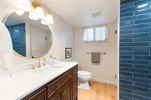 Bathroom vanity featuring a wide basin, brass-finish fixtures, and a circular mirror with integrated lighting