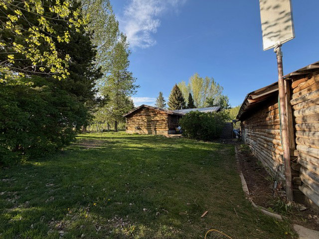 Rustic log structures set amidst a spacious grassy area with mature trees