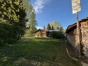 Rustic log structures set amidst a spacious grassy area with mature trees