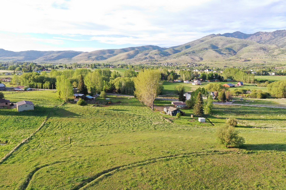 Expansive green fields with distant mountains and scattered residential structures