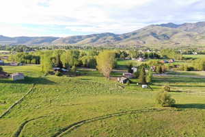 Expansive green fields with distant mountains and scattered residential structures