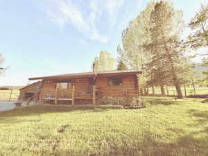 Log cabin exterior featuring a covered porch, stone foundation, metal roof, and a gravel driveway