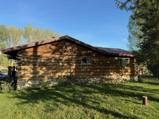 Log cabin exterior featuring a low-pitched roofline and multiple windows