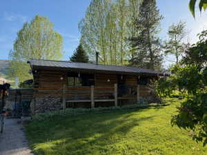 Log cabin exterior featuring a dark metal roof, natural wood siding, and a stone foundation