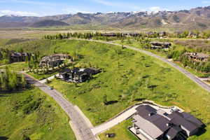 Expansive hillside property featuring a paved driveway, a multi-level residence with a dark metal roof, and distant mountain ranges with snow-capped peaks