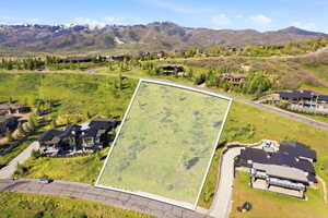 Expansive land parcel featuring natural ground cover, surrounded by mountain terrain, and bordered by paved roadways