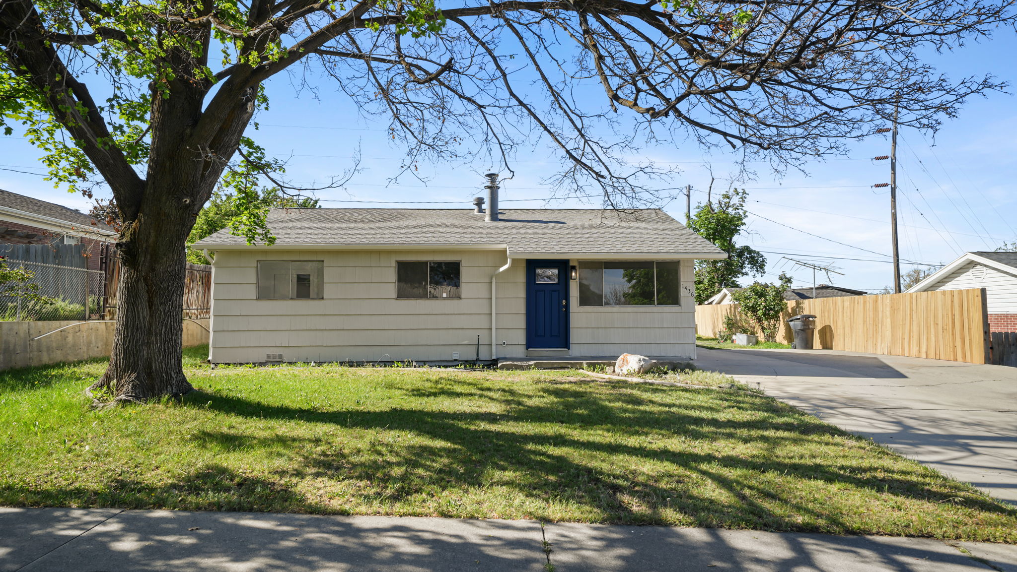Single-story exterior with light-colored siding, a dark blue front door, and a gray shingled roof