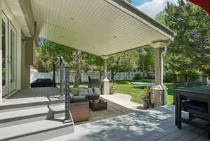 Expansive covered patio featuring a light grey composite deck, white painted support columns, and access to a manicured lawn