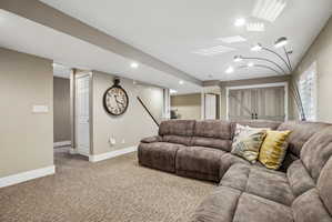 Carpeted recreation room featuring recessed lighting, a barn door, white baseboards, and neutral wall paint