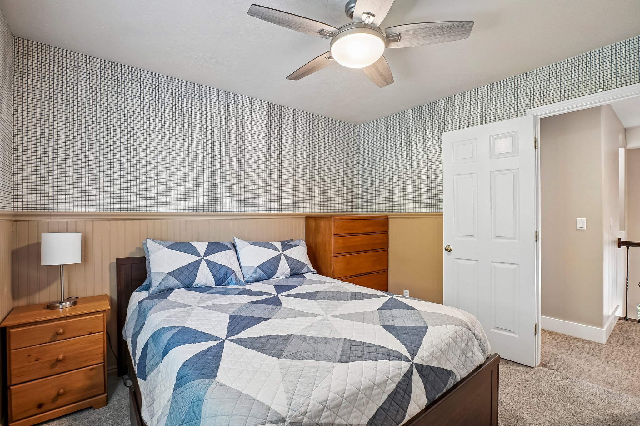 Room featuring textured wallpaper, beadboard wainscoting, and carpet flooring