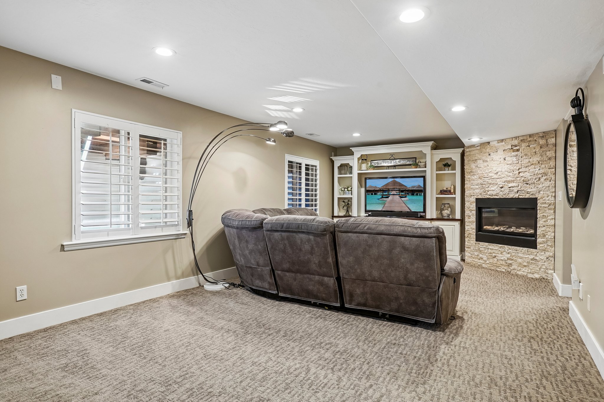 Entertainment space featuring a built-in media center with shelving, a fireplace with stone surround, recessed lighting, and patterned carpeting