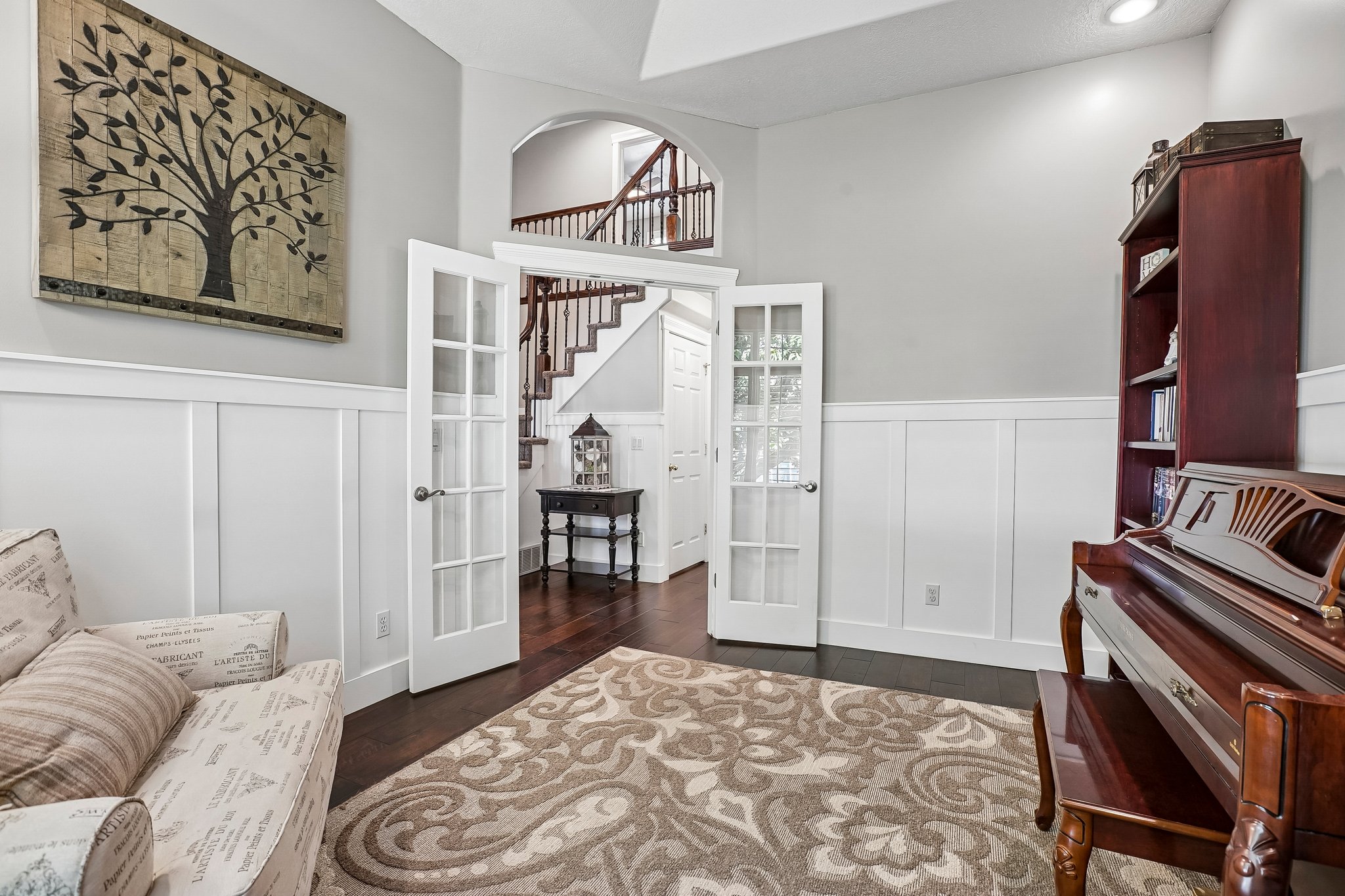 Interior space featuring white board and batten wainscoting, light gray walls, and dark wood-finish flooring