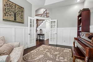 Interior space featuring white board and batten wainscoting, light gray walls, and dark wood-finish flooring
